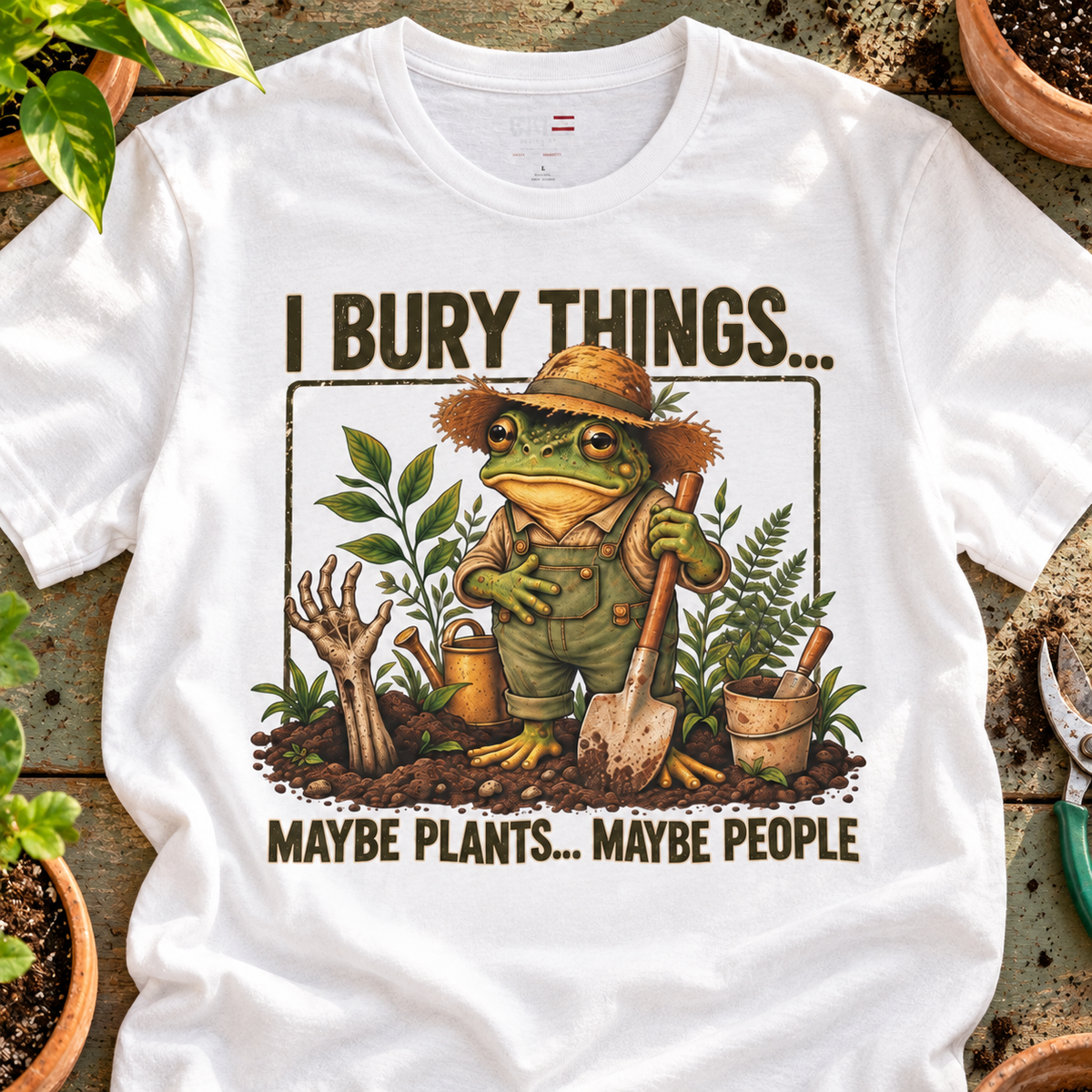 Gardener Frog T-Shirt — "I Bury Things... Maybe Plants... Maybe People" — close-up lifestyle flat lay